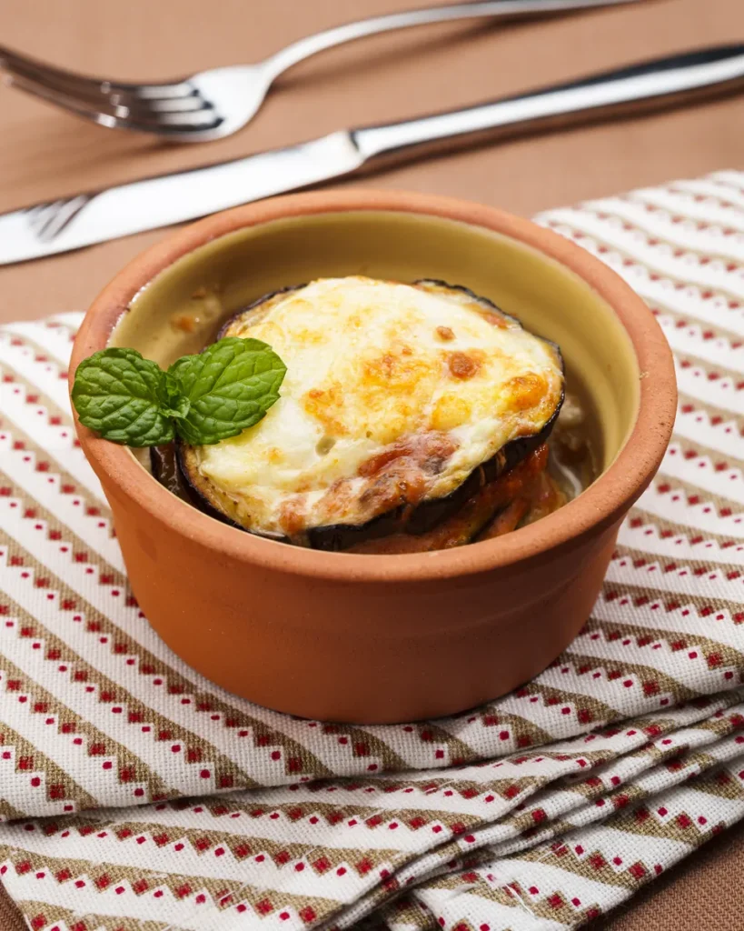 Cocottina di parmigiana di melanzane gratinata, con una foglia di menta