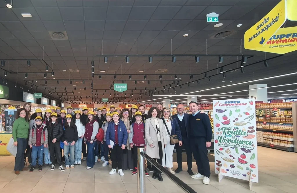 Gruppo di bambini e adulti in posa nel reparto ortofrutta del supermercato