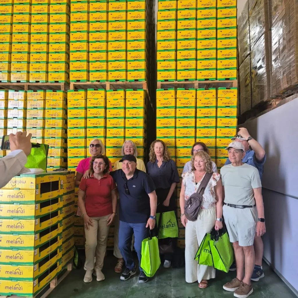 Gruppo di visitatori in posa davanti alle casse Melanzì nel magazzino
